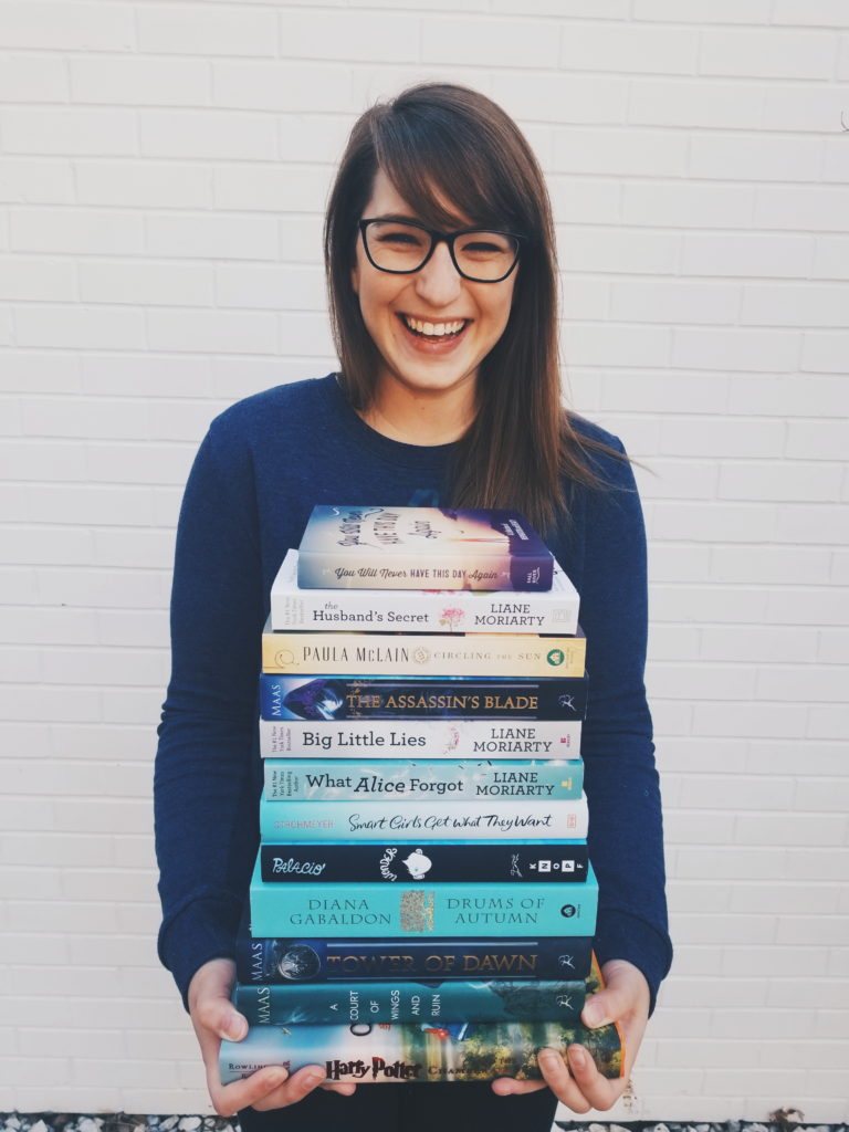 Smiling girl with glasses holding stack of books