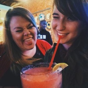 Two girls, drinking margaritas, making funny faces