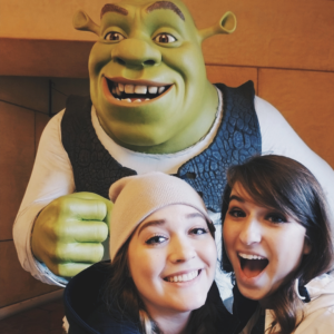 Two girls posing in front of a Shrek statue