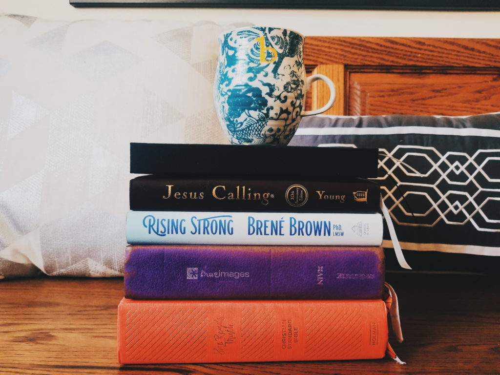 A stack of books used in my morning routine with a cup of coffee on top