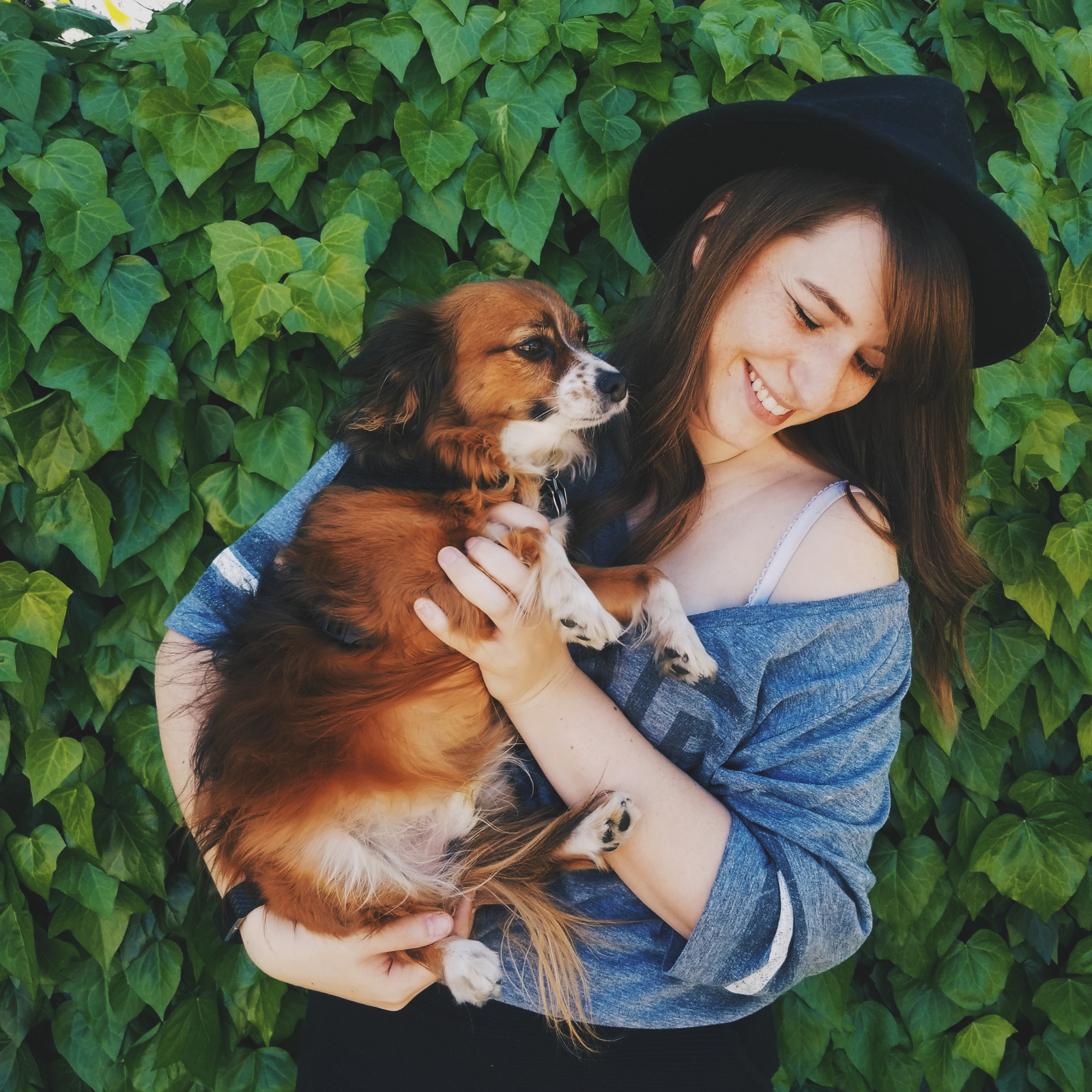 A girl smiling, holding her dog