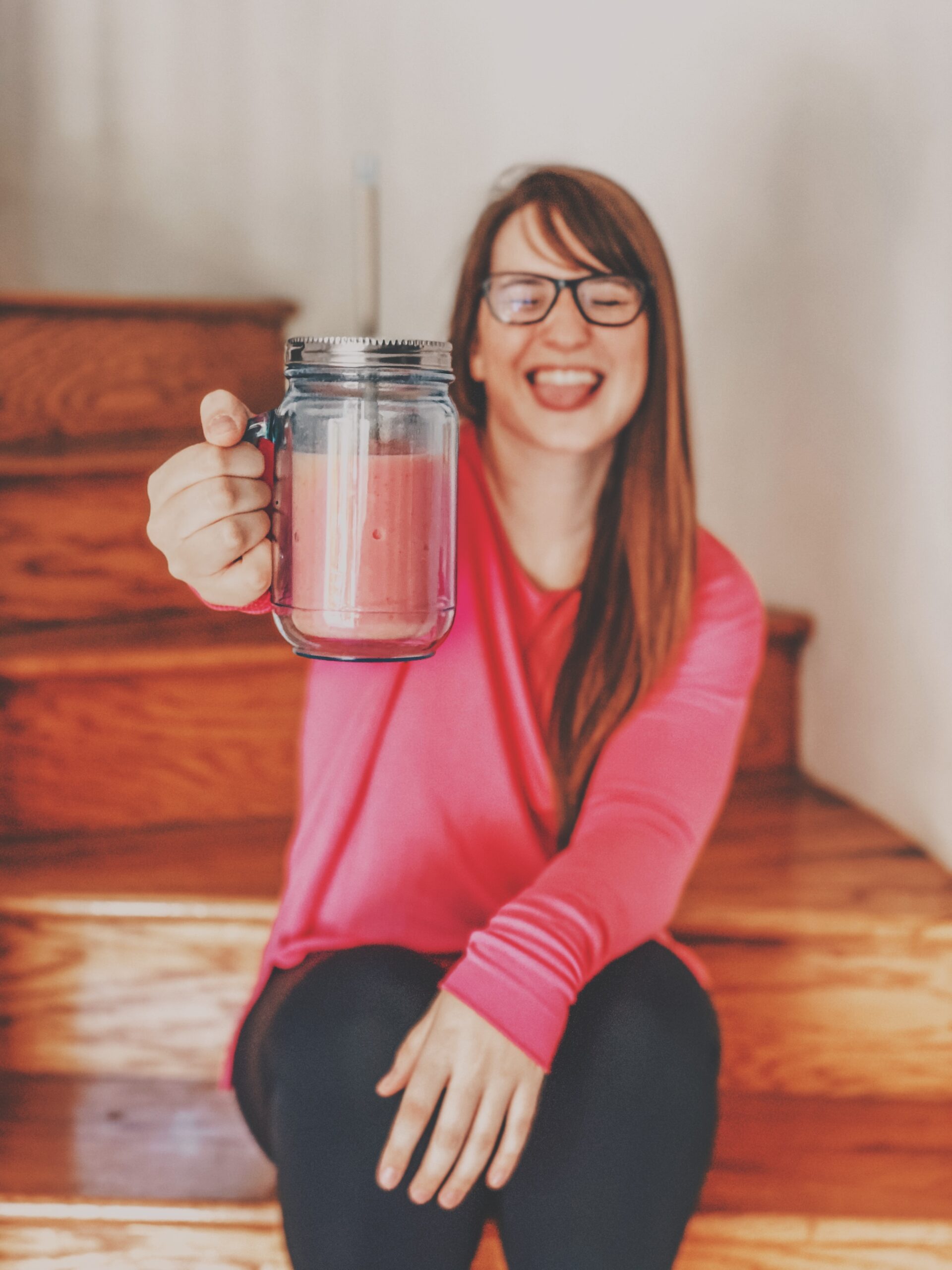 Girl holding up a pink smoothie